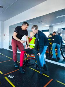 Dwie osoby ćwiczą ewakuację z pomocą krzesła ewakuacyjnego i manekina