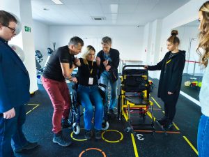 Kilka osób ćwiczy przeniesienie osoby na krzesło ewakuacyjne